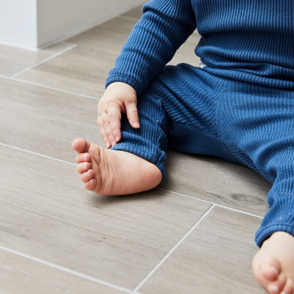 Child in blue outfit sitting on a tiled floor
